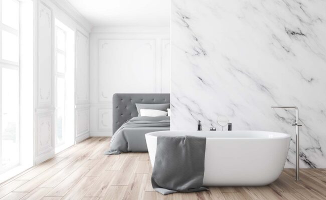 Interior of luxury classic style bedroom with white marble walls, wooden floor and comfortable king size bed. Bathroom with comfortable white tub in foreground. 3d rendering